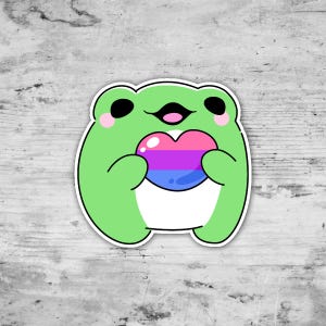 May include: A green cartoon frog sticker holding a heart-shaped object. The heart features pink, purple, and blue stripes, representing the bisexual pride flag. The frog has black eyes and pink cheeks, with a white outline.