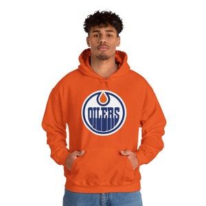 May include: An orange hoodie featuring a navy blue and white Oilers logo on the front. The logo depicts a stylised oil drop and the word "Oilers" in a white outline.
