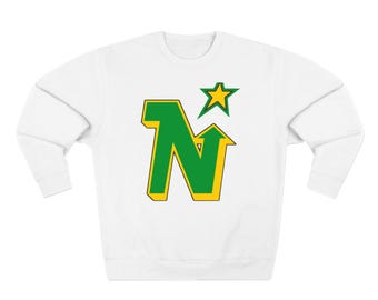 Pode incluir: Camisola branca com uma letra estilizada "N" verde e amarela com uma estrela amarela por cima.