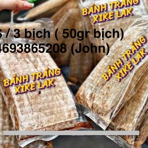 May include: A close-up of three packages of Banh Trang Xike Lak, a type of Vietnamese rice paper cracker. The packages are labeled with the text "Banh Trang Xike Lak" and the price is listed as $10 for three packages, or 50 grams per package. The phone number 4693865208 is also listed on the package.