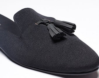 May include: Black fabric slip-on shoes with a tassel detail.