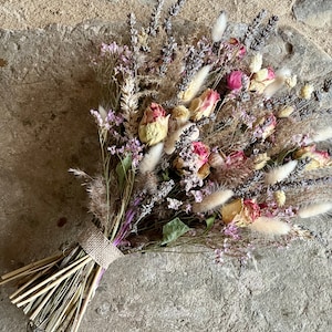 May include: A dried flower bouquet with a variety of dried flowers, including lavender, roses, and grasses. The bouquet is tied with a burlap ribbon.