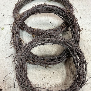 May include: Three brown twig wreaths of varying sizes, stacked on top of each other.