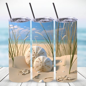 May include: Three stainless steel tumblers with a beach scene design. The tumblers feature a close-up of sand, seagrass, and sand dollars.