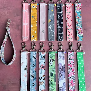 Peut inclure: Assortiment de 15 porte-clés en tissu colorés avec différents motifs. Les porte-clés sont attachés à des anneaux de clés argentés. Les motifs comprennent des motifs floraux, géométriques et à pois.