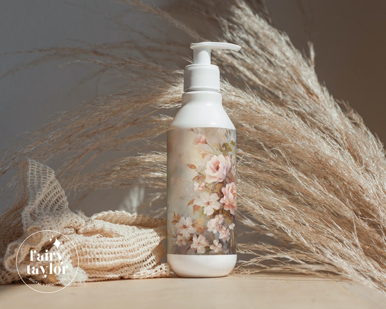 May include: White pump bottle with a floral design featuring pink roses and white blossoms. The bottle has a white pump dispenser and a decorative label with a vintage-style floral pattern. The background includes dried ornamental grass.