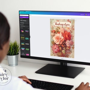 May include: A computer monitor displays a digital floral design with the text "Thinking of you." The design features a bouquet of roses and other flowers in shades of red, pink, and peach. The monitor is on a desk with a keyboard and a small potted plant.