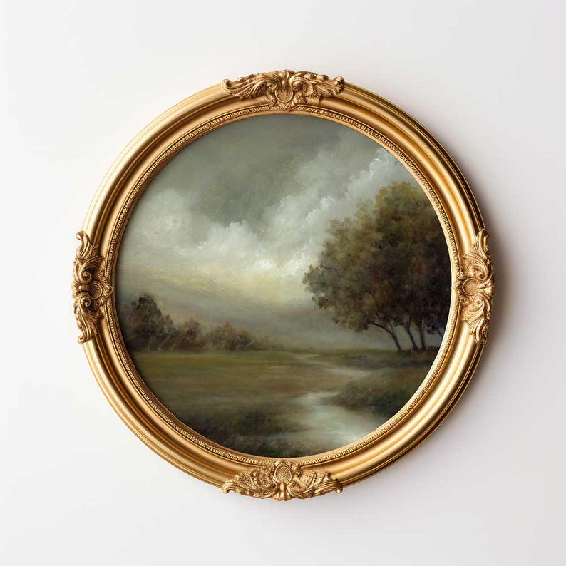 May include: A round landscape painting in an ornate gold frame. The artwork depicts a moody, overcast sky above a grassy field with a small stream winding through the center. A cluster of dark trees stands on the right side of the composition.