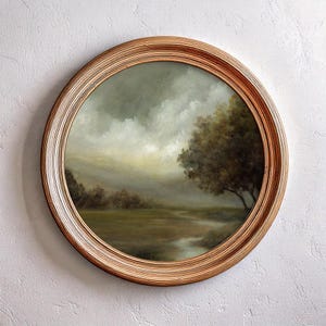 May include: A circular wall art piece featuring an oil painting of a landscape with a large tree, a winding stream, and a cloudy sky. The artwork is enclosed in a round, light brown wooden frame with a textured, ribbed surface design.
