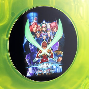 May include: A black disc with a colorful image of characters from the video game Phantasy Star Online: Episode I & II. The text "Phantasy Star Online: Episode I & II" is printed on the disc.