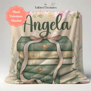 Op de afbeelding: Zachte velours deken met een ontwerp van gestapelde antieke boeken, vastgebonden met een lint. De boeken zijn in groen- en cr&egrave;metinten, met gouden details. De naam "Angela" is geschreven in een scriptletter, met bloemmotieven.