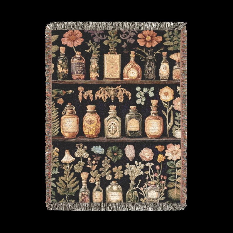 Op de afbeelding: Een geweven tapijtdeken met een zwarte achtergrond met daarop een vintage apotheekrek met rijen glazen flessen gevuld met kleurrijke vloeistoffen. De flessen zijn omringd door verschillende botanische illustraties van bloemen, bladeren en kruiden.