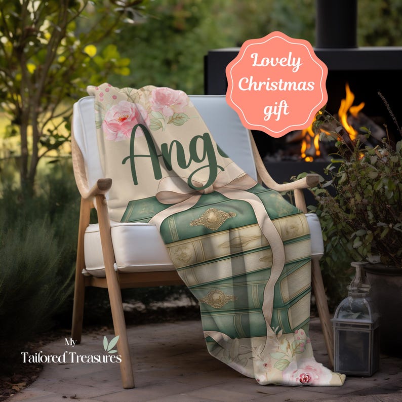 Op de afbeelding: Een gepersonaliseerde deken met een ontwerp van groene boeken, vastgebonden met een lint. De deken is versierd met roze rozen en de naam "Ang" in groene letters. Een "Lovely Christmas gift" label is zichtbaar. Een ideaal kerstcadeau.