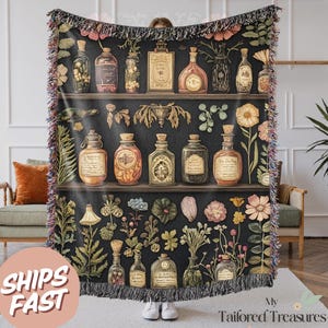 Op de afbeelding: Een geweven tapijtdeken met een vintage botanische illustratie van glazen flessen gevuld met drankjes en kruiden. Het ontwerp is geplaatst tegen een donkere achtergrond met een herhalend patroon van planken en bloemmotieven.