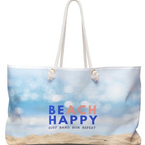 May include: White canvas tote bag with a blue and white beach scene and the text "Beach Happy Surf Sand Sun Repeat".