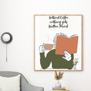 Puede incluir: Una impresión artística enmarcada con el texto "Without coffee nothing gets written. Period." representa a una persona leyendo un libro y sosteniendo una taza de café. La impresión cuelga sobre un sillón gris con un cojín blanco, junto a una mesa auxiliar negra.