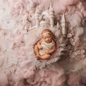 May include: A sleeping baby girl wearing a white lace outfit lies in a fluffy pink and white nest with a white castle prop behind her. The castle is surrounded by pink and white clouds.