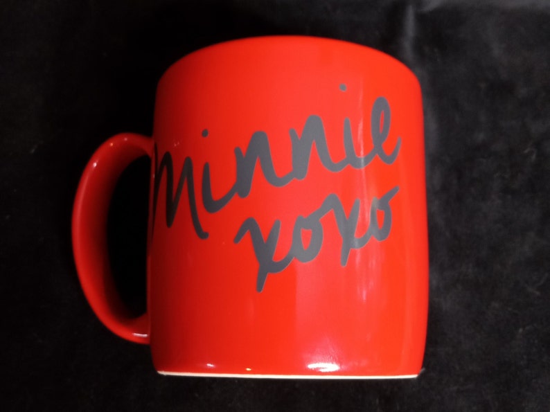 May include: Red ceramic mug with a black handwritten inscription that says "Minnie xoxo".