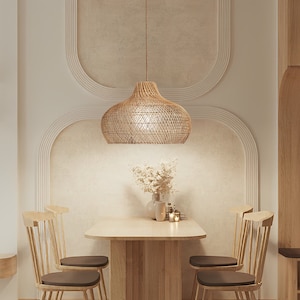 May include: A woven rattan pendant light hangs over a wooden dining table with four chairs. The table is set with a vase of dried flowers and candles.