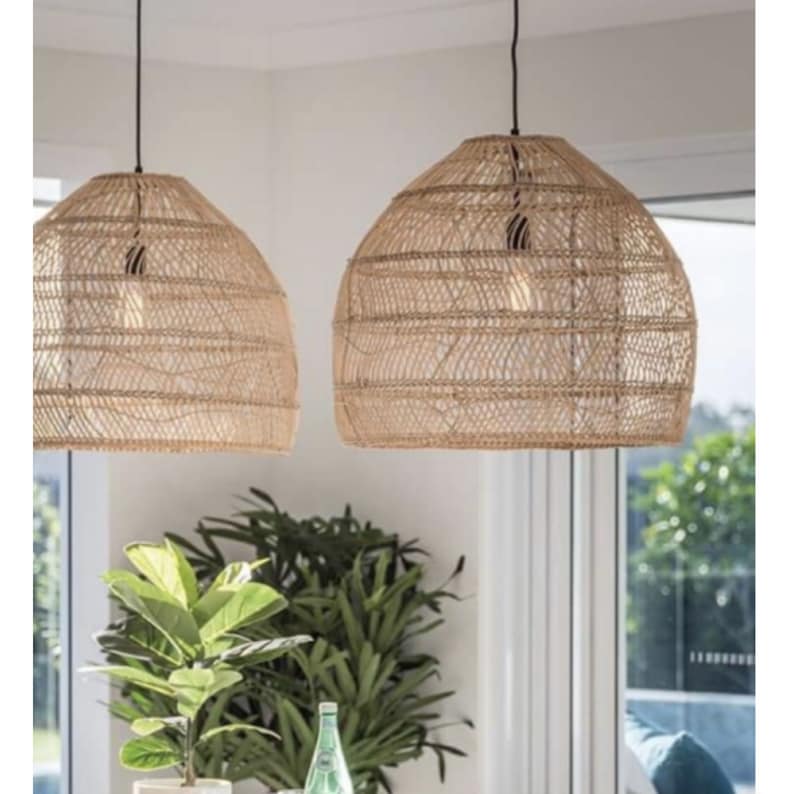 May include: Two natural woven pendant lights hang from the ceiling in a modern kitchen. The lights are made of a light brown, natural material and have a round, dome shape.