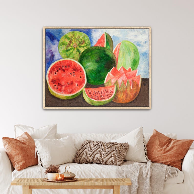 May include: Watercolor painting of watermelons in various forms: whole, sliced, and carved. The painting features vibrant red and green hues, with the text "VIVA LA VIDA" on a watermelon slice. The artwork is framed in a light wood frame.