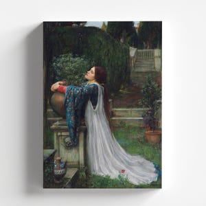 May include: A woman in a white gown and blue robe stands in a garden, leaning against a stone urn. She has her head tilted back and her eyes closed, as if in prayer. The garden is lush and green, with flowers and trees in the background.