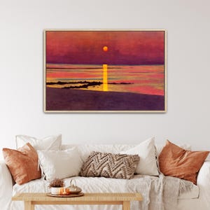 Pode incluir: Uma impressão de arte de parede retangular emoldurada retratando um pôr do sol sobre um corpo de água calmo. A cena apresenta um sol laranja vibrante, um reflexo amarelo brilhante na água, silhuetas rochosas escuras e um céu roxo e vermelho.