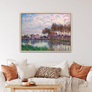 Op de afbeelding: Een ingelijst landschapsschilderij met een rivierscène met een stenen brug, gebouwen en hoge bomen onder een zachte, pastelkleurige lucht. Het kunstwerk toont zichtbare penseelstreken in tinten blauw, roze, groen en bruin, met een rustig uitzicht.