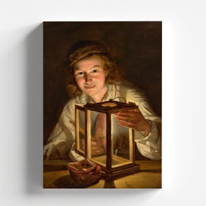 May include: A young person with light brown hair holds a lantern with a glass panel and a wooden frame. The lantern is lit and casts a warm glow on the person's face. The person is wearing a white shirt and is sitting at a table. There is a small, red pouch on the table.