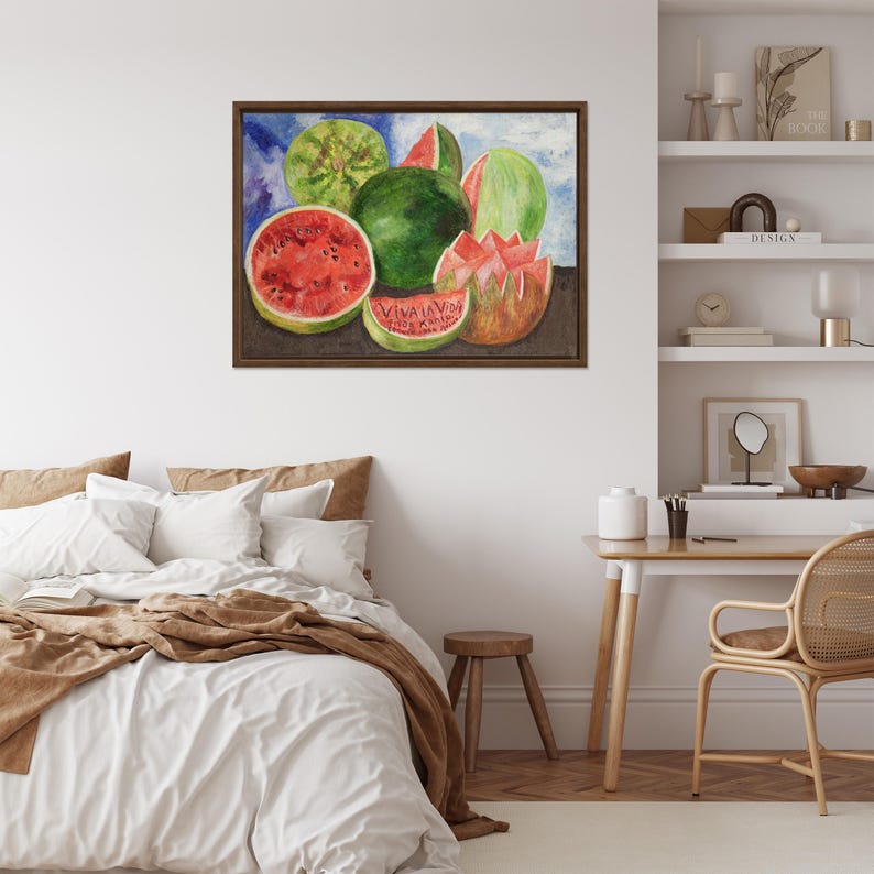 May include: Watercolor painting of watermelons in various forms: whole, sliced, and cut. The painting features vibrant red and green hues, with the text "VIVA LA VIDA" visible on one slice. The artwork is framed in a dark brown wooden frame.