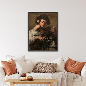 May include: Framed art print of a classical painting. The artwork depicts a person with dark curly hair, wearing a white garment, and holding a vase of flowers. The painting has a dark, moody color palette with a black frame.
