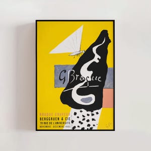 May include: A framed art print featuring a yellow background with a black abstract shape and white accents. The print includes the text "G Braque" and additional text at the bottom. The artwork has a modern, graphic style.