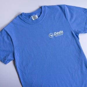 May include: A light blue t-shirt with a white logo that says "Dodo Airlines" and a cartoon dodo bird in a circle.