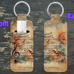 May include: A brown leather keychain with a musical note design. The keychain has a silver key ring and a pocket for a small item. The design features a treble clef and sheet music.
