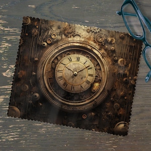 Op de afbeelding: Een vierkante microvezel reinigingsdoek met een steampunk klokontwerp. De doek is bruin en goudkleurig, met een textuur. Een bril in teal ligt op een houten oppervlak.