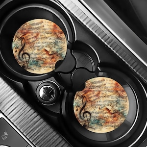 May include: Two round car coasters with a vintage music sheet design. The coasters feature a treble clef and musical notes in shades of brown, blue, and white.