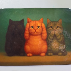 May include: A rectangular decorative item featuring three cartoon cats in a 'see no evil, hear no evil, speak no evil' pose. The cats are black, orange, and tabby, set against a green background.