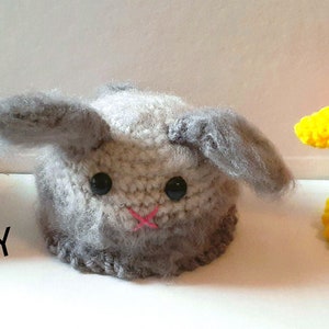 May include: Three crocheted bunny plushies in different colours and styles. The first bunny is white with brown and black accents and colourful beads. The second bunny is grey with a pink nose. The third bunny is orange, yellow, pink, and blue with colourful beads and sequins. The text "PATTERN ONLY" is visible in the image.