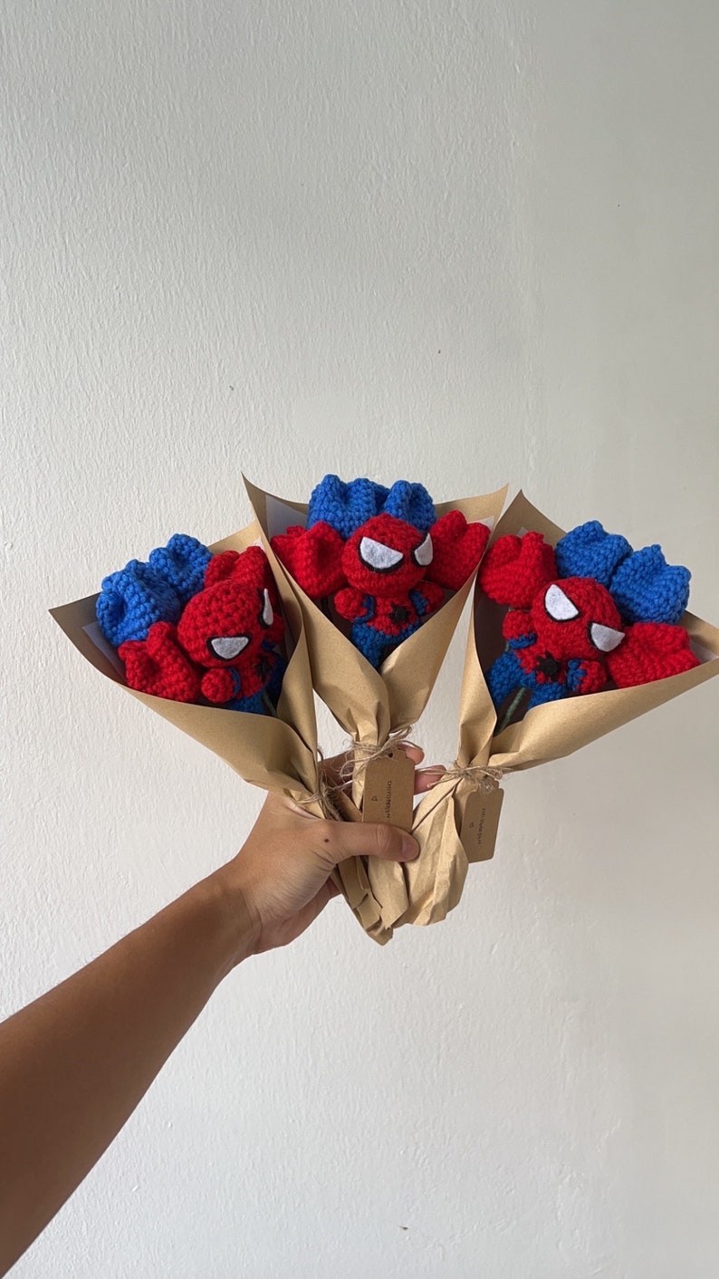 May include: Three crocheted bouquets of red and blue Spiderman characters wrapped in brown paper.