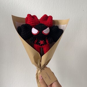 May include: A crocheted red and black Spider-Man character in a brown paper bouquet with a tag that says "CHIVY GARDEN" with a heart symbol.