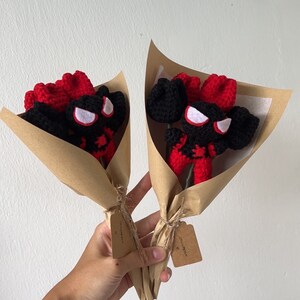 May include: Two bouquets of crocheted red and black spider-man figures wrapped in brown paper with a small tag that says "smile you're beautiful".
