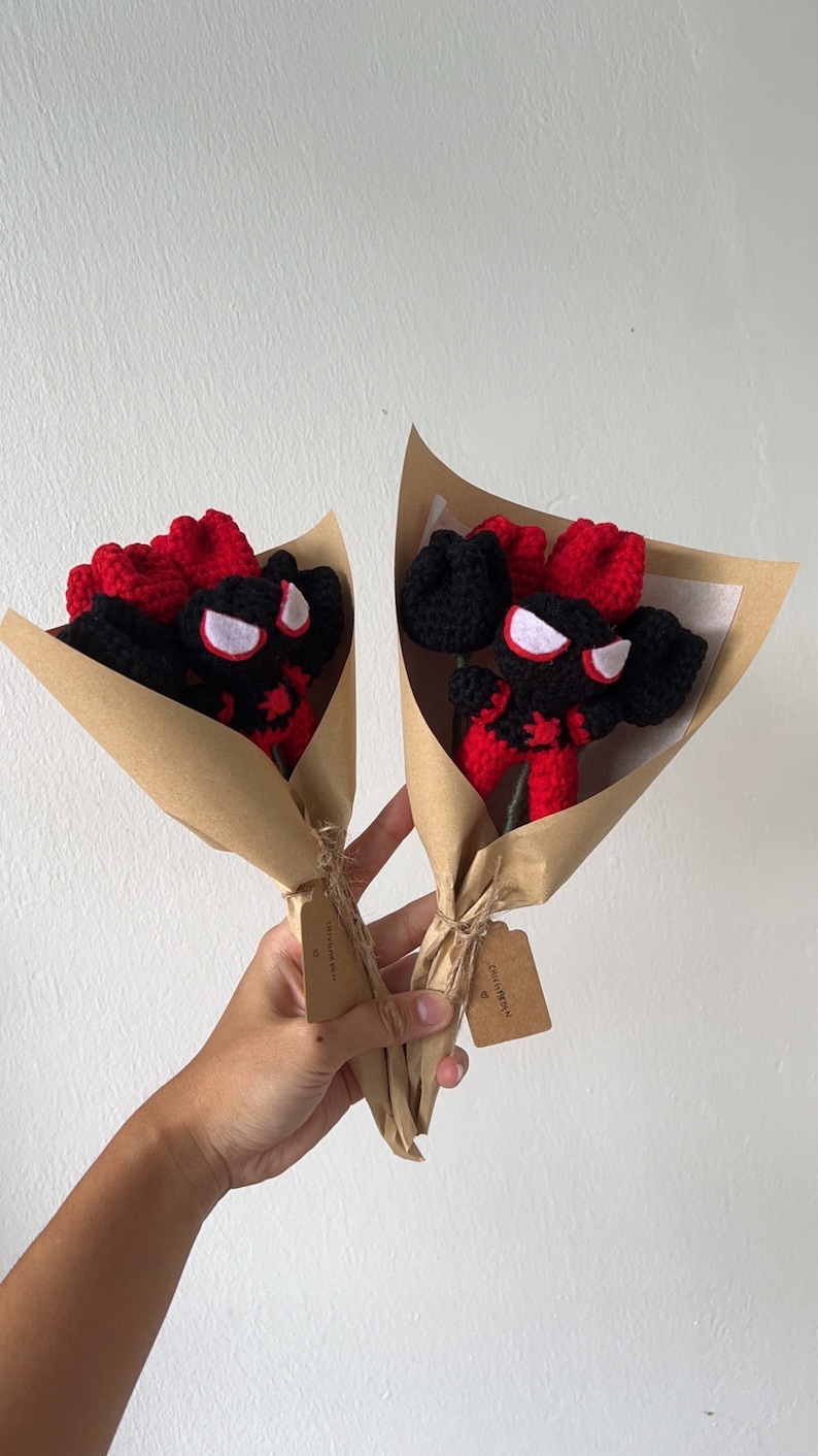 May include: Two bouquets of crocheted red and black spider-man figures wrapped in brown paper with a small tag that says "smile you're beautiful".