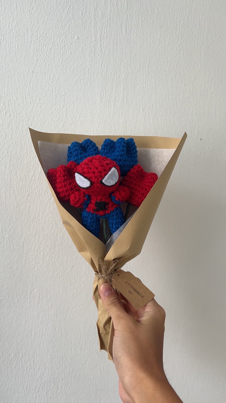 May include: A brown paper bouquet with a crocheted Spiderman figure in the center. The bouquet is tied with twine and has a small brown tag that says "CHIVARDEEN" with a heart symbol.