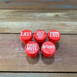 May include: Five red round buttons with white text. The buttons read "EJECT", "EJECTO SEATO. CUZ", "PASSENGER EJECT", "BACK SEAT MUTE", and "NITROUS".