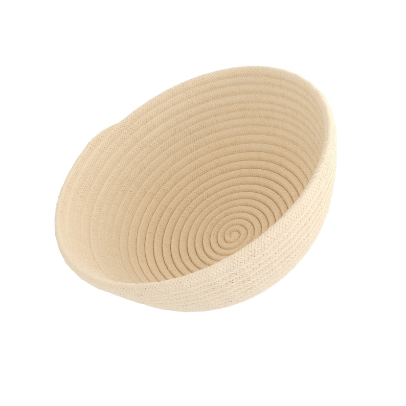 May include: A beige, oval-shaped woven basket with a spiral design at the base. The basket is made of tightly coiled rope, creating a textured surface. The interior is a lighter shade of beige.