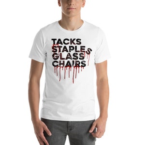 Puede incluir: Camiseta blanca con un gráfico negro que dice "Tacks, Staples, Glass, Chairs" con pintura roja goteando.