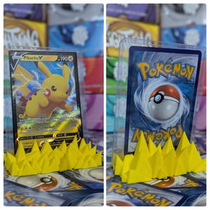 May include: Two Pokemon trading cards displayed on yellow plastic card holders. The card on the left is a Pikachu V card. The card on the right is a Pokemon card with a Pokeball in the center.