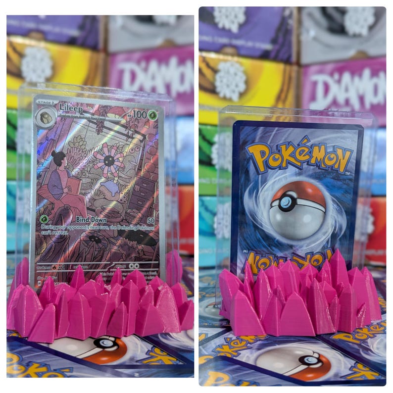 May include: Two Pokemon trading cards displayed on pink plastic card holders. The card on the left is a Lileep card with a light pink background and a picture of a Pokemon with a flower on its head. The card on the right is a Pokemon card with a blue background and a picture of a Pokeball.