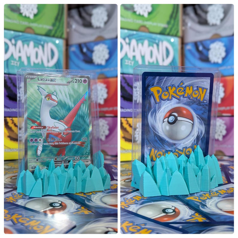 May include: Two Pokemon trading cards are displayed in clear acrylic cases on a turquoise blue 3D printed stand. The stand is shaped like a row of jagged peaks. The cards are displayed on a background of Pokemon booster packs.