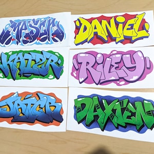 Puede incluir: Seis pegatinas blancas con letras de estilo graffiti de colores. Los nombres en las pegatinas son Mason, Daniel, Kaizer, Riley, Jacer y Daxien.